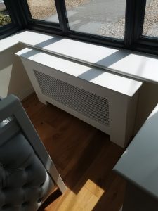 Window with a white wooden radiator cover beneath it