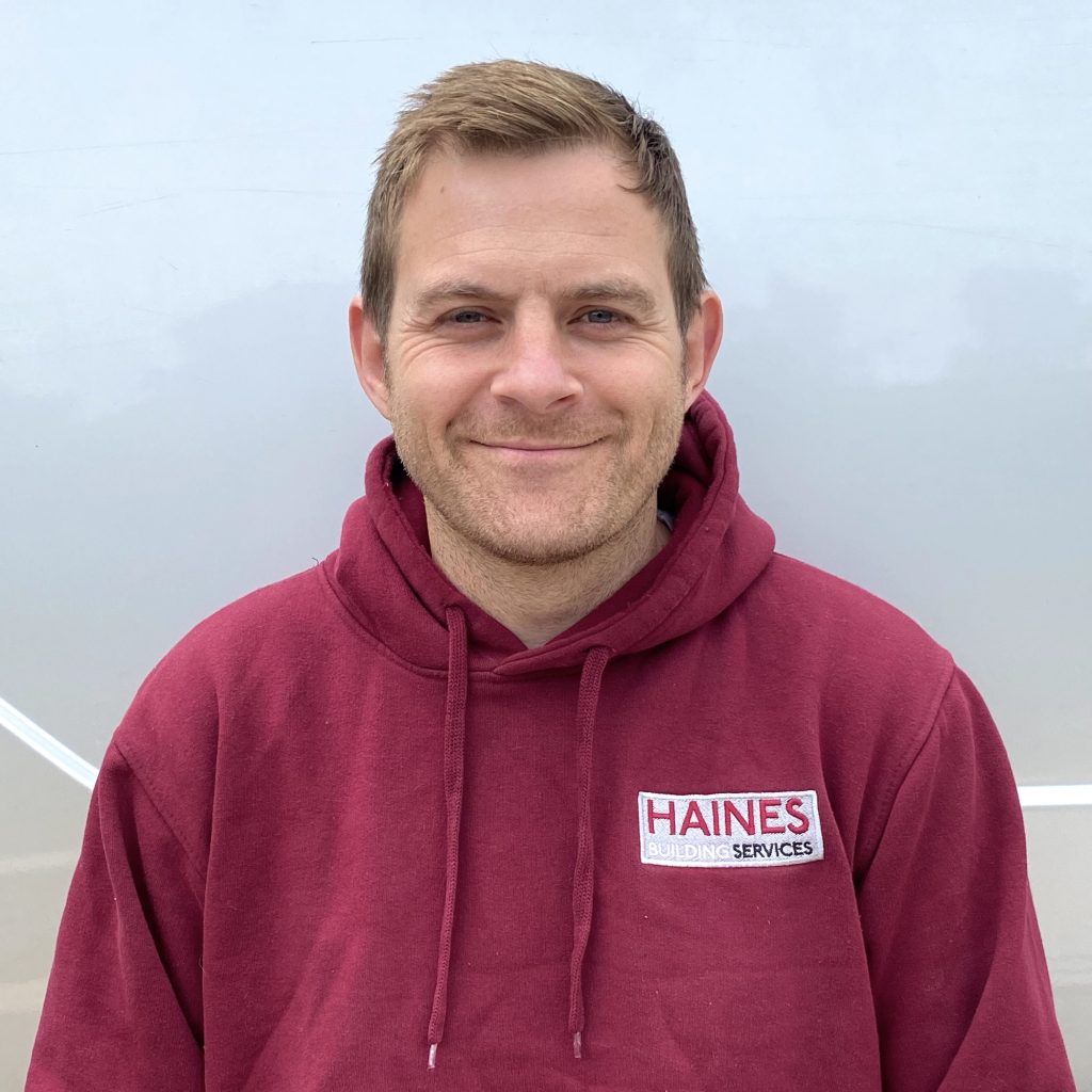 A man with a burgundy hoodie on which says Haines Building Services