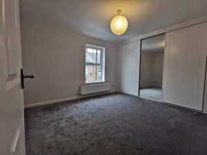 A room with grey carpet and built in wardrobes
