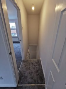 A staircase with grey carpet and white walls