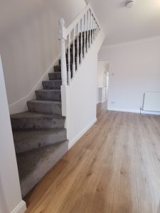 A room with a wooden floor and a staircase going upstairs