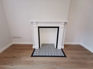 A white fireplace with black and white tiles