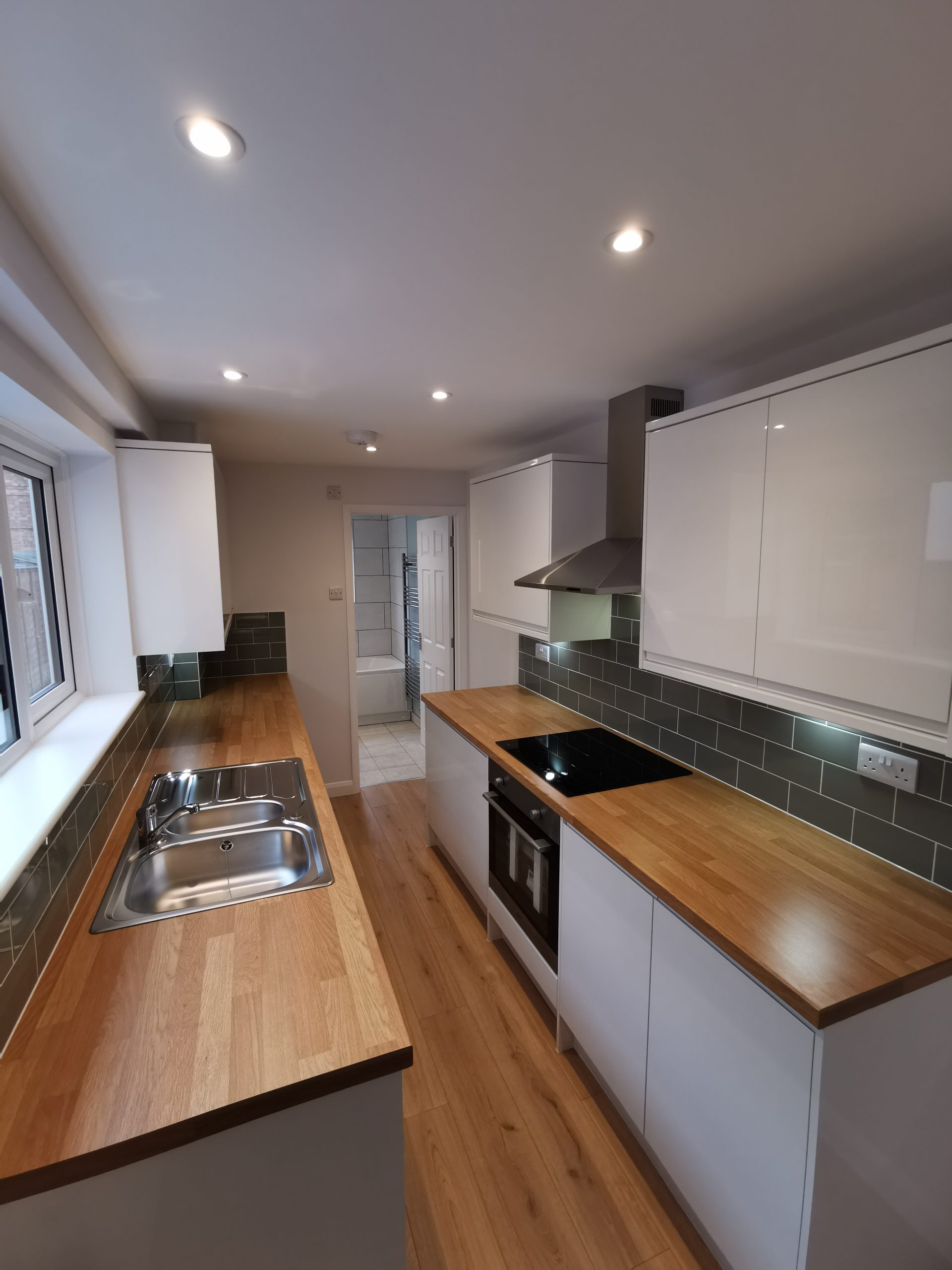 A beautiful kitchen with green tiles and white cupboards