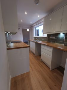 A beautiful kitchen with green tiles and white cupboards