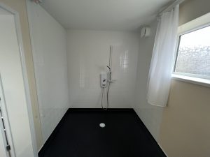 A level access bathroom with black floor and white tiles