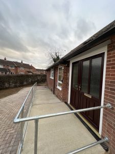 A red brick house with a concrete ramp and metal railings