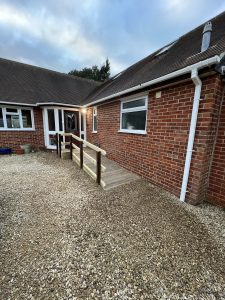 Gravel outside a red brick house with a wooden ramp