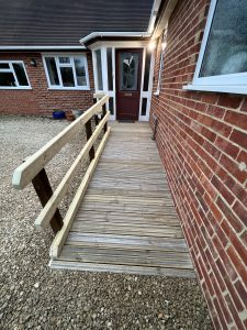 Gravel outside a red brick house with a wooden ramp