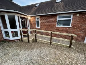 Gravel outside a red brick house with a wooden ramp