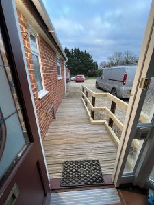 Gravel outside a red brick house with a wooden ramp