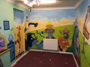 A room with a mural painted with children's characters