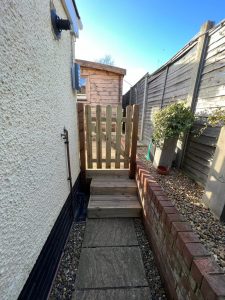 A pebbledash wall with a wooden gate