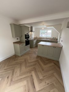 A green kitchen with oak floor and patterned tiles