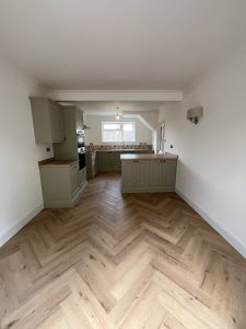 A green kitchen with oak floor and patterned tiles