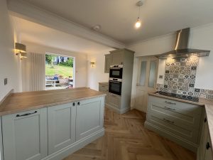 A green kitchen with oak floor and patterned tiles