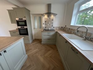 A green kitchen with oak floor and patterned tiles