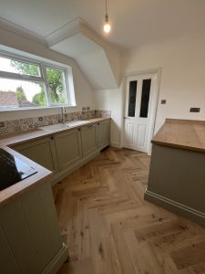 A green kitchen with oak floor and patterned tiles