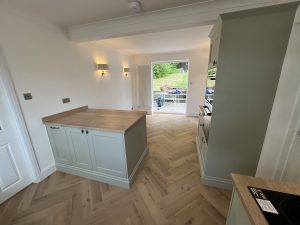A green kitchen with oak floor and patterned tiles