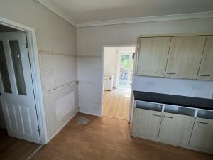A kitchen with pale wooden cupboards and black worktop