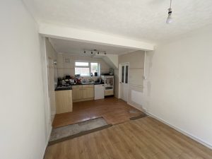 A kitchen with pale wooden cupboards and black worktop
