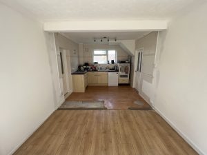 A kitchen with pale wooden cupboards and black worktop