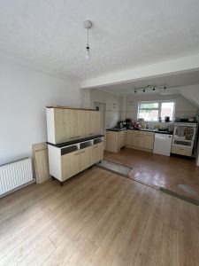 A kitchen with pale wooden cupboards and black worktop